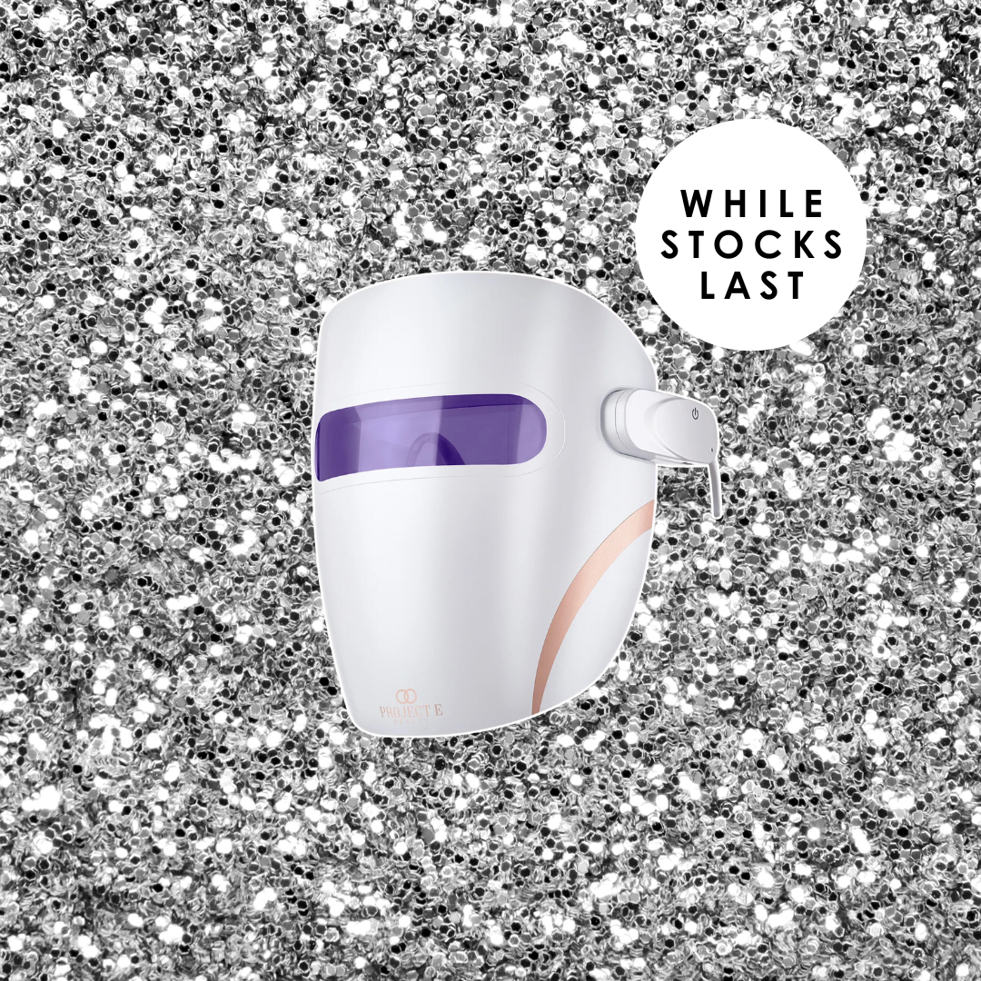 A Project E Beauty red light therapy mask displayed on silver glitter with a badge reading "While Stocks Last."