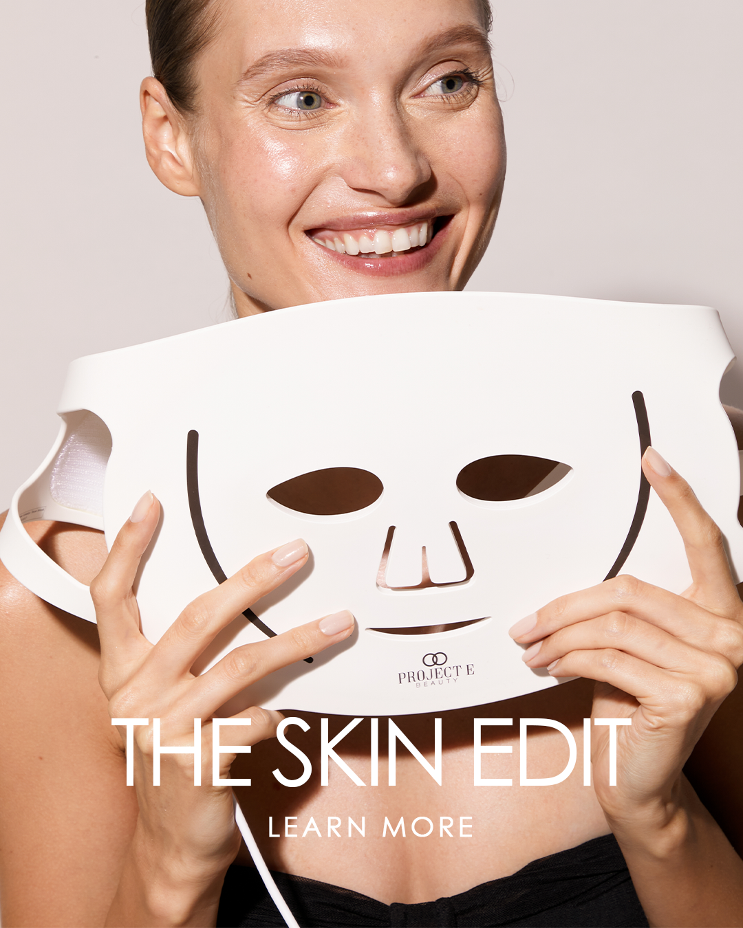 A woman holding an LED light therapy mask with "The Skin Edit" title